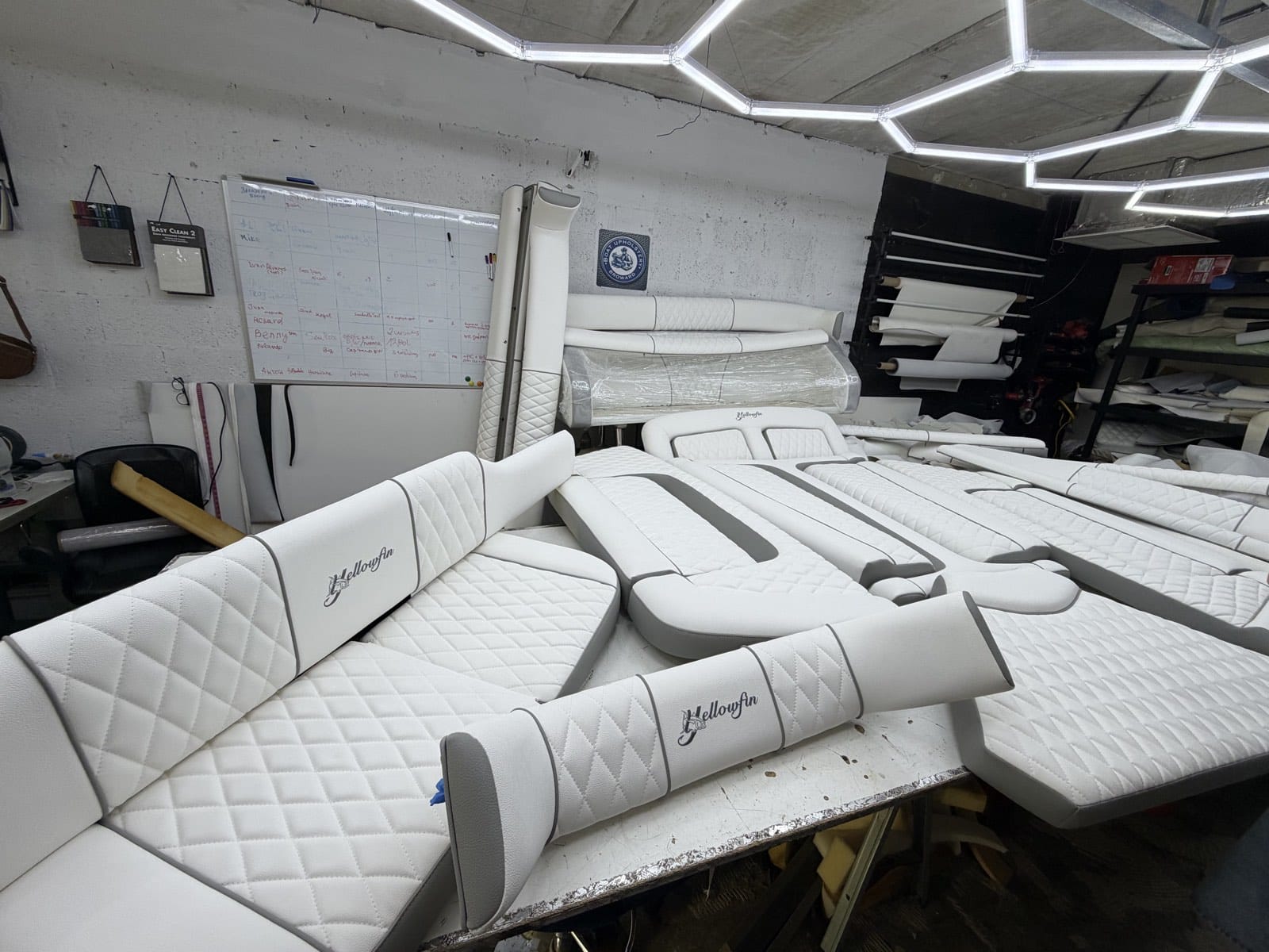 Custom cushions and bolsters arranged beneath workshop lights, with white diamond stitching and gray trim