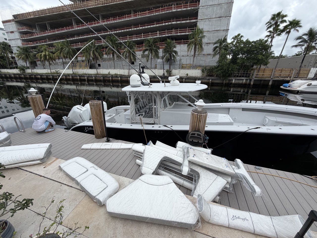 Wrapped replacement cushions and bolsters laid out on the dock beside the boat for installation
